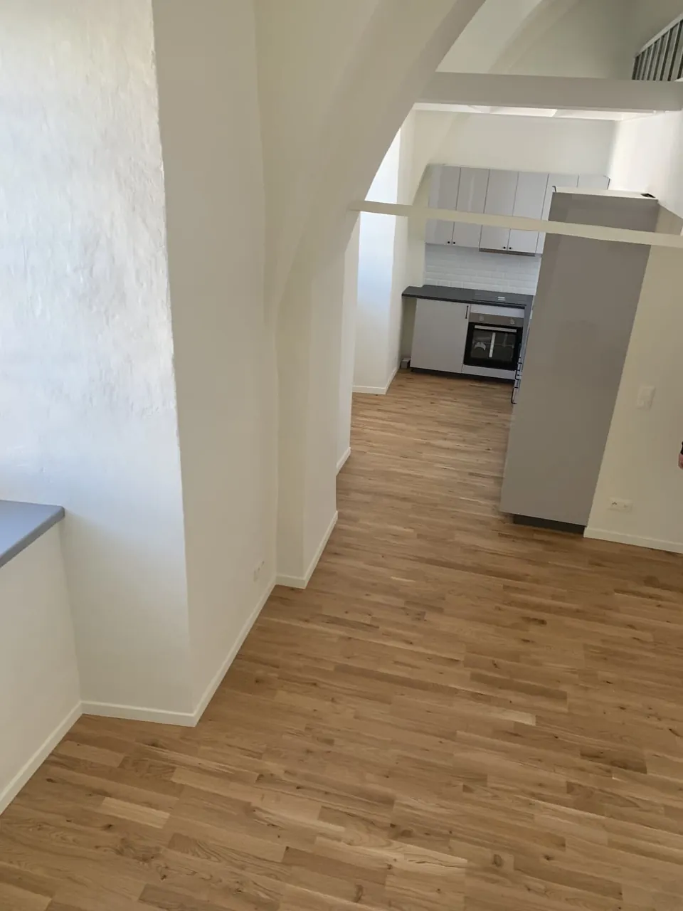 Cuisine ouverte aménagée sous une voûte avec parquet chêne