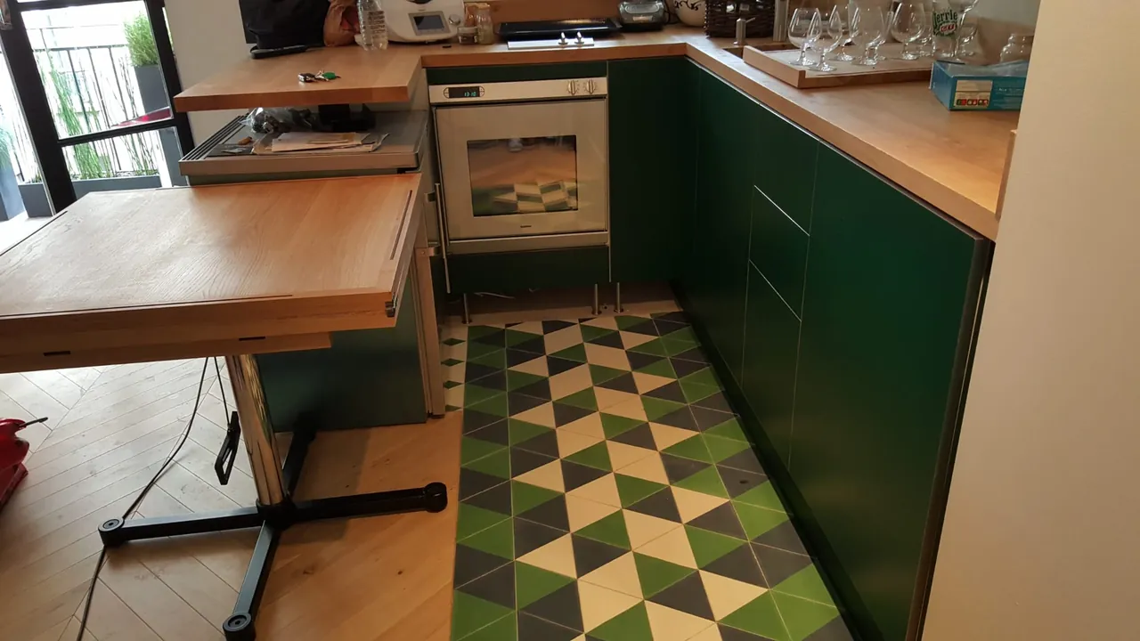 Cuisine sur mesure laquée verte avec sol en carreaux de ciment, réalisée à Neuilly