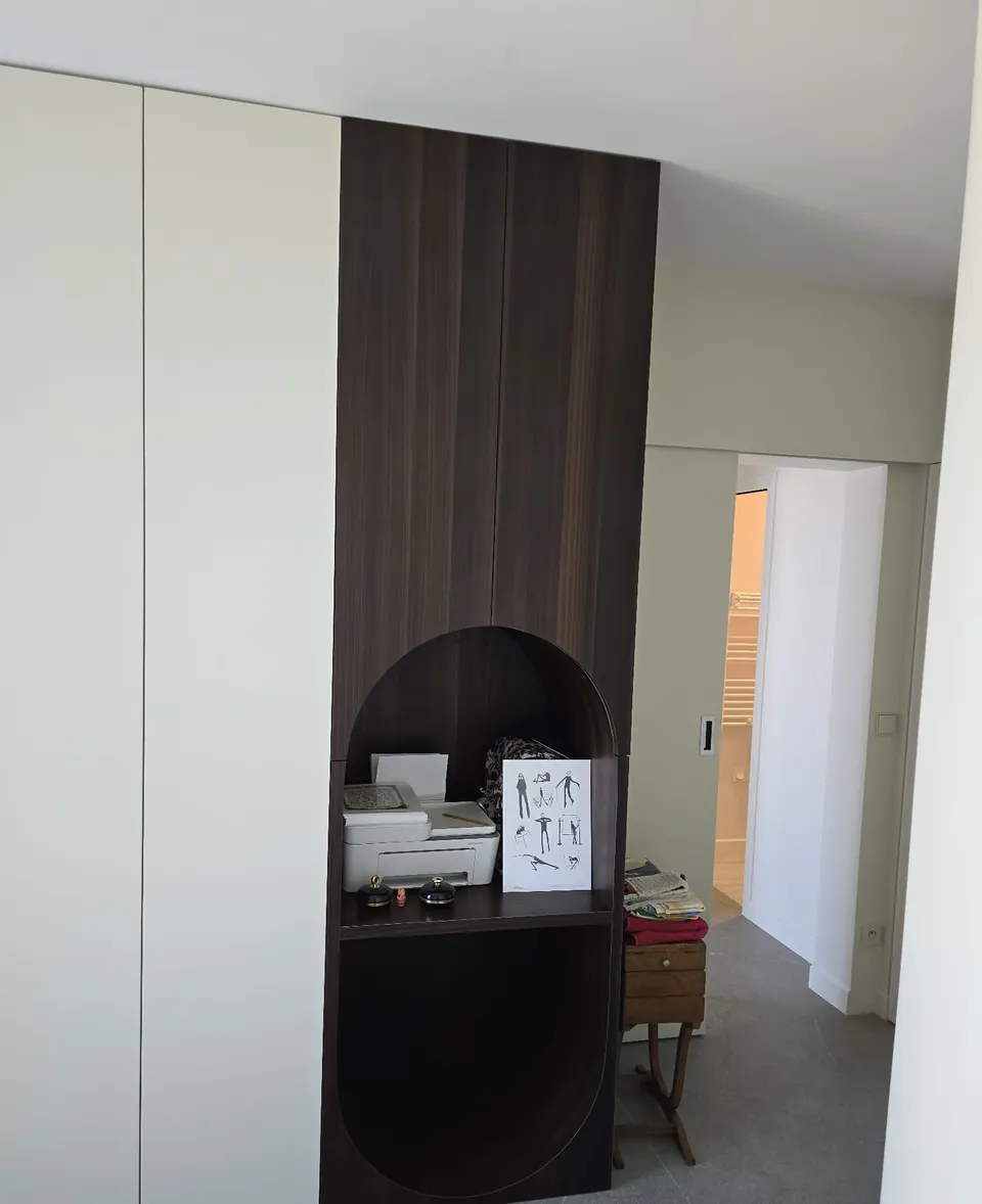 Dressing et menuiseries en bois foncé intégrées dans un couloir blanc