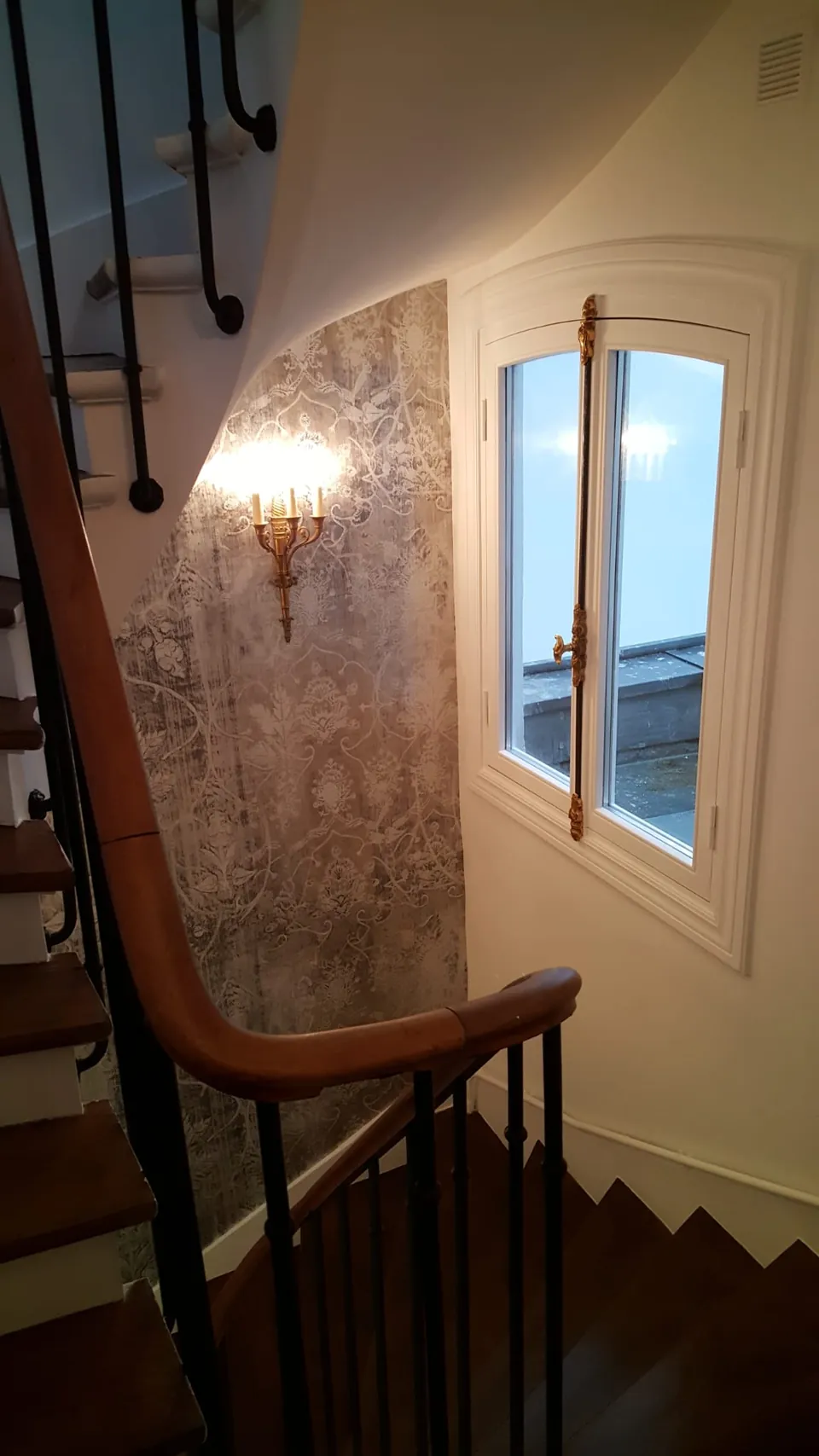 Escalier en bois avec main courante vernie, enduit décoratif et applique