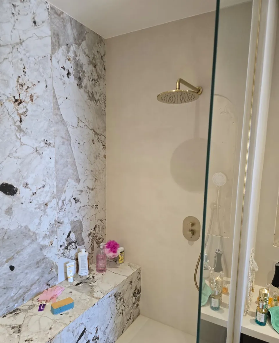 Douche à l'italienne avec paroi vitrée et mur en pierre naturelle veinée