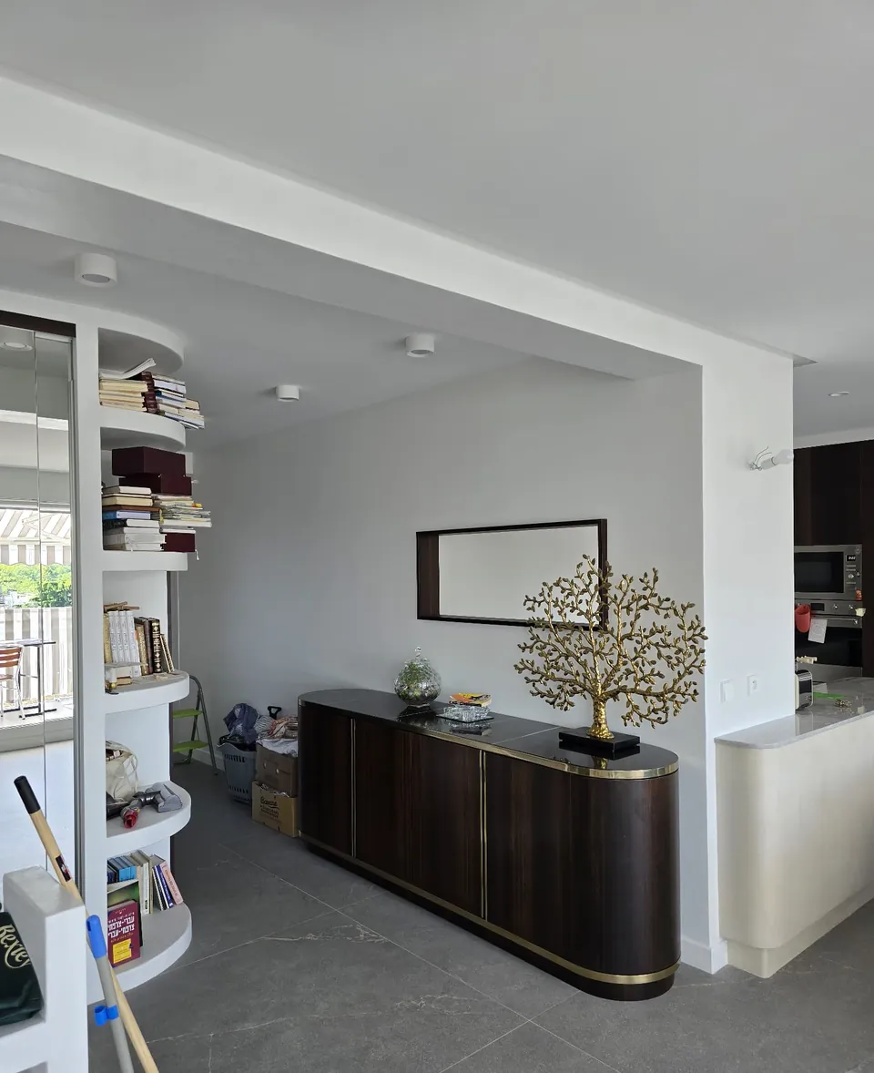 Séjour rénové avec niches et étagères sur mesure autour d'un buffet en bois foncé
